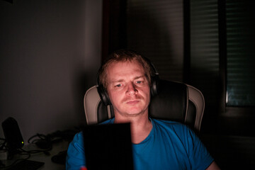 Fototapeta premium Man wearing headphones playing video games at night