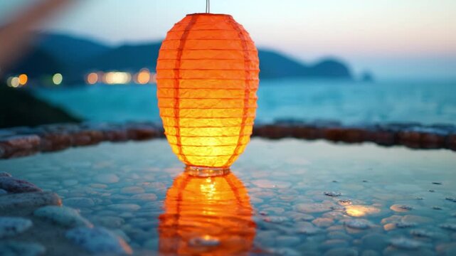 An exquisite orange lantern reflects beautifully in still water, enhancing the serene coastal atmosphere at dusk as gentle waves lap nearby.