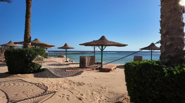 Panoramic view of empty beach in the morning with sun loungers, umbrellas and a hanging hammock