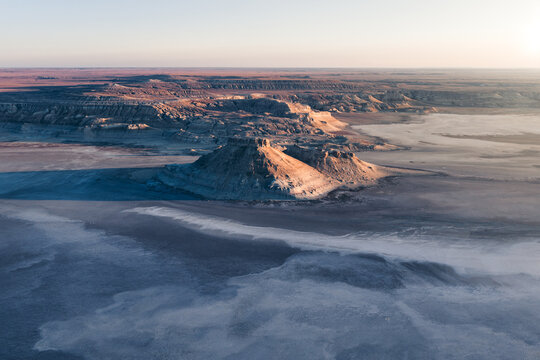 Aerial view of Karynzharyk rock formations rising from the vast salt flats and desert landscape in Karakiya District, Mangystau Region, Kazakhstan.