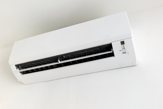 Wall-mounted split air conditioner unit on white wall, indoor climate control.