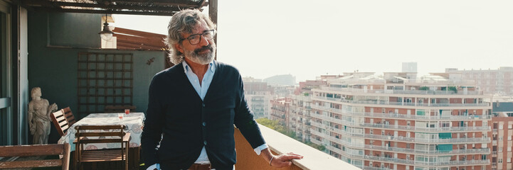 Obraz premium Senier enjoys the view standing on the balcony. Panoramic