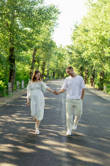 Fototapeta premium Couple walking hand in hand on a scenic rural road in summer