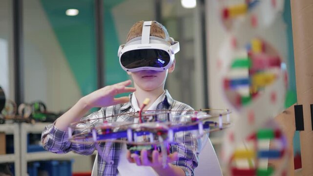 Concept technology in education of school. Boy manipulating flying drone prototype in makerspace classroom with vr headset and gesture control.