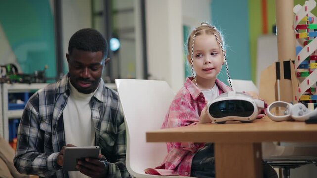 African American Man and young girl interacting with vr headset and tablet at education school.
