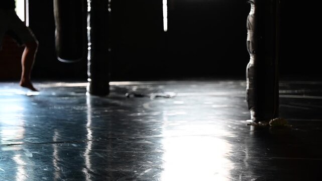 Dark lit gym boxing, martial arts, man working out, kickboxing, mat space, cinematic in silhouette bokeh background video, martial arts Wellnes theme