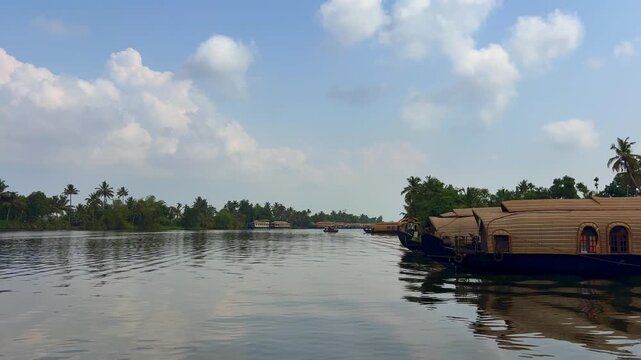 Traditional houseboats docked along the tranquil backwaters of Kerala, surrounded by lush tropical scenery