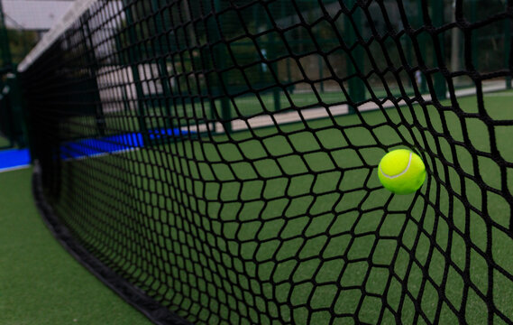 Padel or tennis ball in the net. Background with copy space. Sport court and ball. Social media template. Promotion for padel and tennis events.