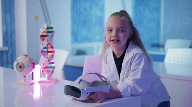 Concept technology in education of school. Girl in lab coat holding virtual reality headset on science classroom table.