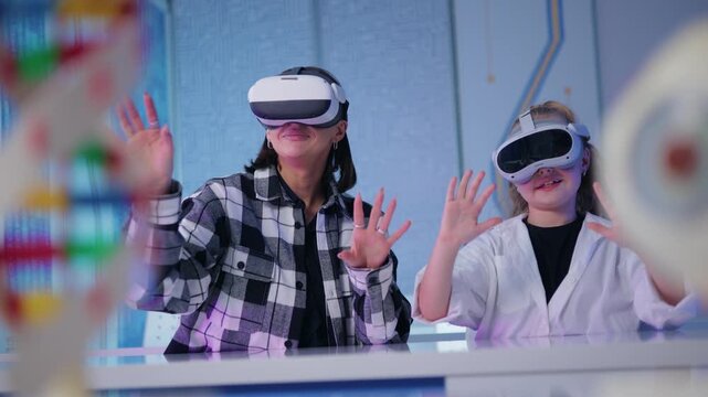 Woman teacher and kid girl wearing virtual reality headsets interacting at tech lab table with hand gestures, Concept technology in education of school.