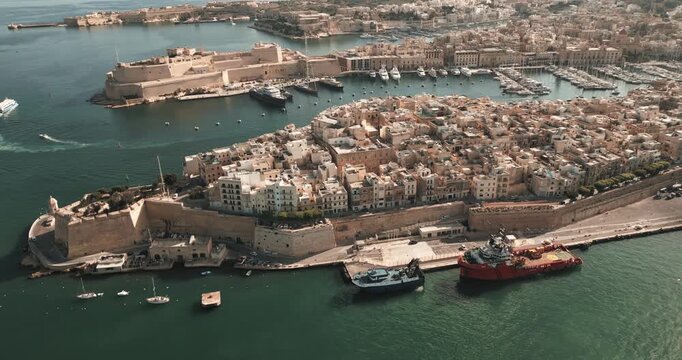 Aerial Drone View of Birgu and Fort St. Angelo, Malta Austria. daytime slow motion shot with boats surrounding the coast.