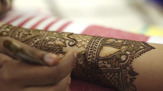 Close-Up shot of Applying Mehndi (Henna) on Bride's hand at her Indian Wedding in India