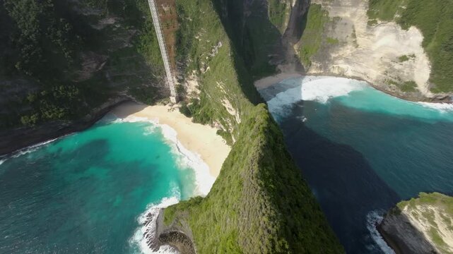 Cinematic drone shot of the iconic TRex shaped cliffs at Kelingking Beach, Nusa Penida, Bali. Showcases crystal clear turquoise water and white sand for travel and wellness content.