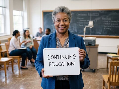 Smiling mature African American woman holds a continuing education sign in a classroom with students