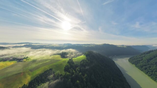 Drone footage transitions from a tiny planet effect into a natural aerial view. Sunrise light and light morning mist reveal the landscapes of the M&uuml;hlviertel and Danube Valley in Upper Austria.