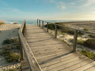 Wooden walkway leading to the scenic ocean shore at Furadouro beach in Ovar Portugal, captured on a bright and calm summer afternoon © anammarques