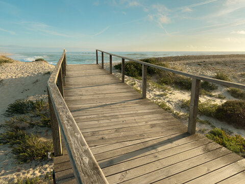 Wooden walkway leading to the scenic ocean shore at Furadouro beach in Ovar Portugal, captured on a bright and calm summer afternoon