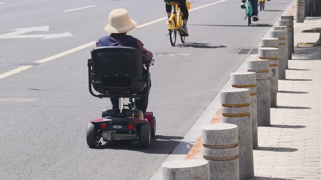 Elderly Woman Riding Electric Mobility Scooter on City Street in Beijing, China
