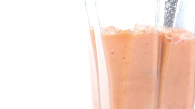 中身がオレンジスムージーのミキサーが回っている3