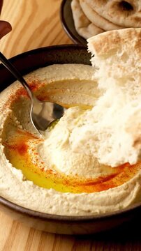 Macro View Of Smooth Hummus With Olive Oil Pool Paprika Sprinkle And Pita Bread Being Dipped In Natural Lighting Creamy Middle Eastern Food Commercial
