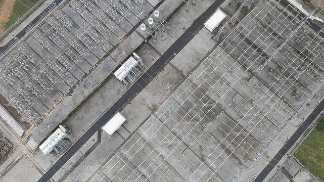 Aerial view of an electricity substation with high-voltage power lines, metal structures, and transformers arranged in a grid pattern on a concrete surface in Portugal.