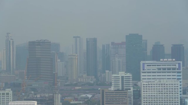 Aerial pan right view of a modern city skyline completely covered in heavy smog and toxic air pollution during the day
