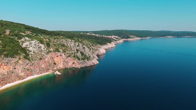 Aerial panorama of Plaža Pod Črnice near Vrbnik, Croatia. Spectacular rocky coastline, emerald Adriatic waters, and a remote beach hidden beneath colorful limestone cliffs on Krk Island