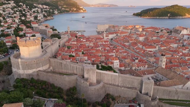 Dubrovnik old town walls aerial panorama slide shot flying starting from the round tower (Tvrdava Minceta) to sea