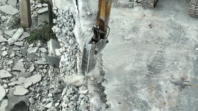Drone view capturing heavy machinery breaking reinforced concrete pavement, highlighting road reconstruction, civil engineering projects, transportation upgrades and public infrastructure maintenance.