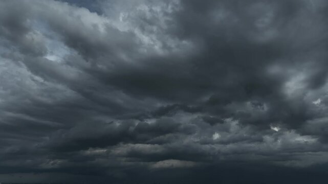 Drone perspective capturing dense black clouds stretching across the horizon, representing dramatic weather conditions, climate uncertainty, and the raw energy of an incoming storm system. 4k.
