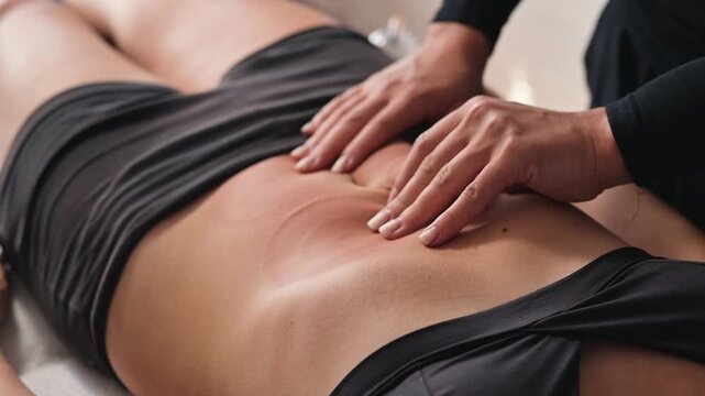 therapist performs a manual therapy procedure on a patient lying face down on a treatment table. The therapist uses specific techniques to address discomfort in the patient's back area