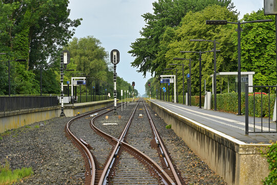 Small rural train station with curved railway tracks in green landscape, Groningen