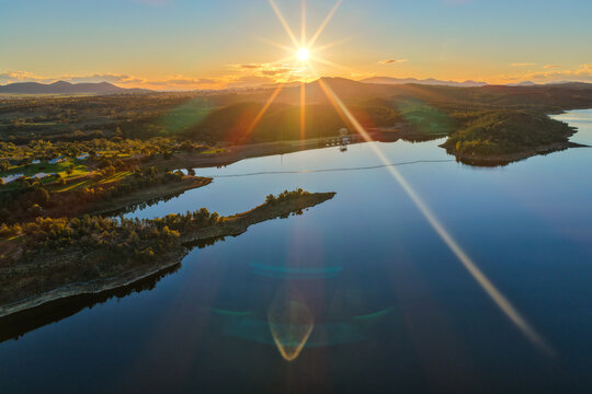 Aerial view showcasing the Lake Keepit dam wall and surrounding rural landscape at sunset, with warm golden light illuminating the reservoir and engineering infrastructure in NSW, Australia.