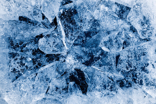 Broken ice. Crushed textured ice with cracks on a black background, in cold blue tones.
