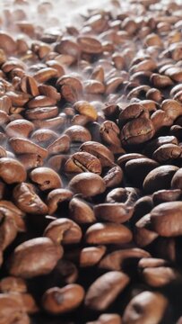 Steaming roasted coffee beans background with selective focus.