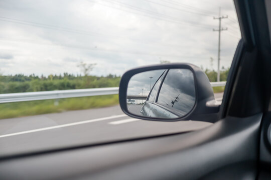 Driving on the open road, viewing the highway landscape reflected in a car's side mirror.