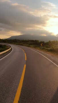 Empty road in Norwegian mountains at sunrise, vertical travel landscape.