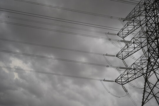 Parte de una torre de alta tensi&oacute;n con detalle de estructura y de cables de electricidad con cielo de nubes, referencia a energ&iacute;a