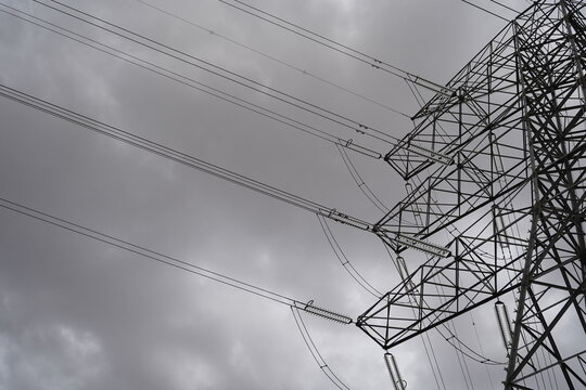 Parte de una torre de alta tensi&oacute;n con detalle de estructura y de cables de electricidad con cielo de nubes, referencia a energ&iacute;a