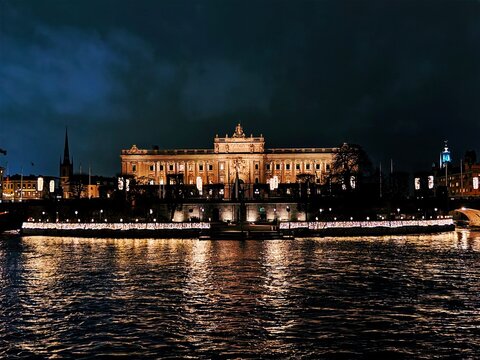 Stockholm, Sweden-Nov.27th 2025: Night view architectural facade of the Swedish Parliament House (Riksdagshuset) in Stockholm, illuminated and reflecting on the water surface.