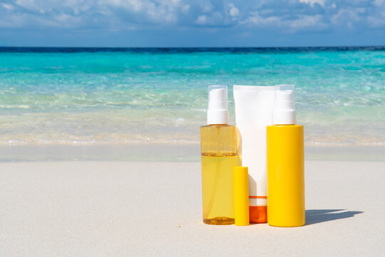Sandy summer beach background with set of sunscreen lotion bottle templates for skin and lips