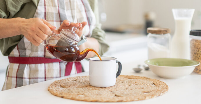 Woman Pouring Tea Into Mug
