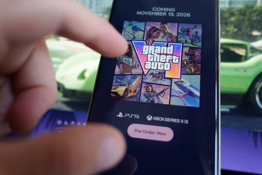Close up of a hand interacting with a smartphone screen displaying a pre-order page for Grand Theft Auto VI, video game digital marketing and mobile commerce concept