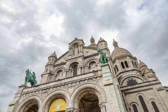 View of the Sacre-Coeur Basilica in Montmartre, Paris, France, showcasing its beautiful architecture under a cloudy sky.