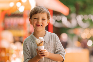 Fototapeta premium Happy boy eats ice cream in the park in summer