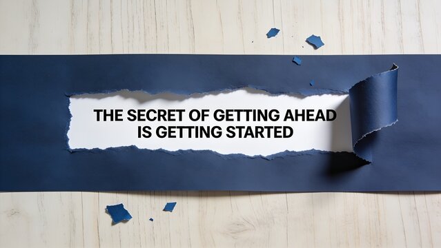Inspirational message about getting started printed on white paper revealed through a torn dark blue paper strip against a light wooden surface in bright studio lighting