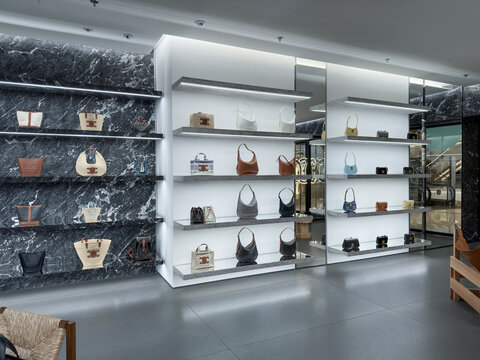 SHANGHAI, CHINA - JUNE 25, 2026: Interior of a Celine Paris luxury fashion boutique featuring clothing racks, footwear displays, handbags, minimalist shelving, wooden chairs, and contemporary retail f