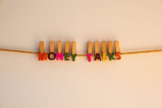 Money Talks written in cute colourful alphabet wooden clips fixed to rope against wall 