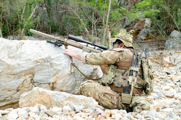 Fototapeta premium Snipers in camouflage uniforms conceal themselves behind rocks their rifles ready to fire at the enemy during combat.