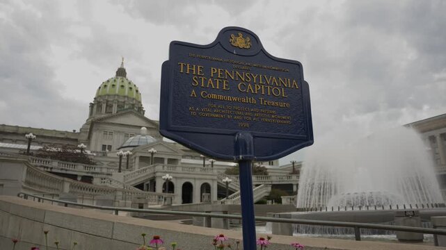 Description:
Tilt and pan establishing shot of the Pennsylvania State Capitol sign and fountain in Harrisburg Pennsylvania on a clear summer day showcasing the historic government complex and surround